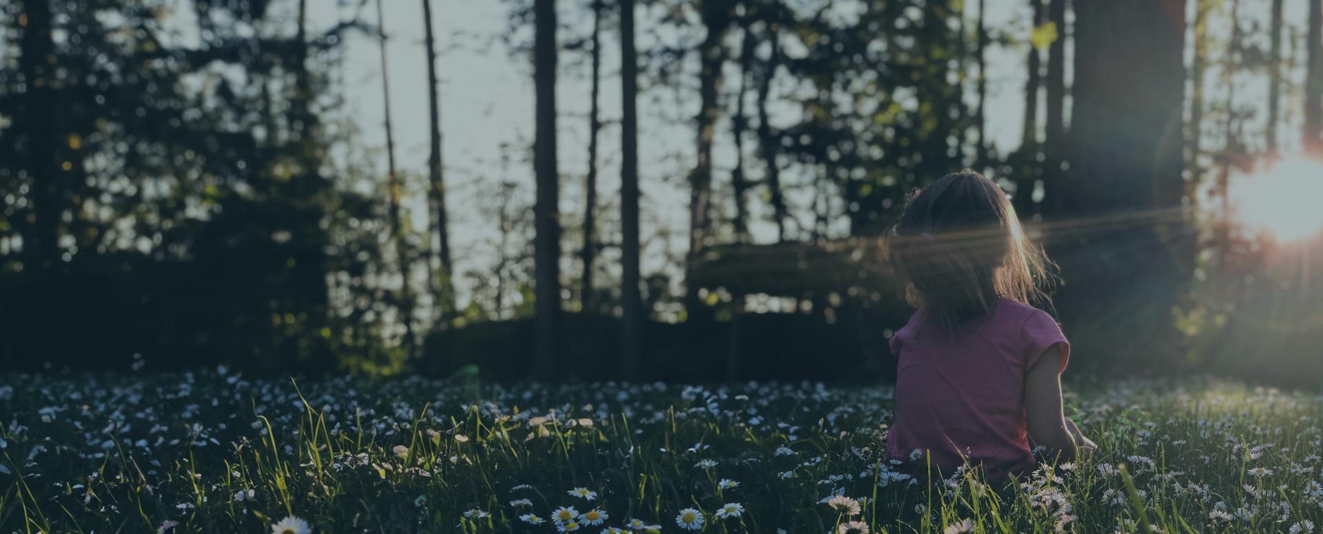 Pige sidder i en blomstermark